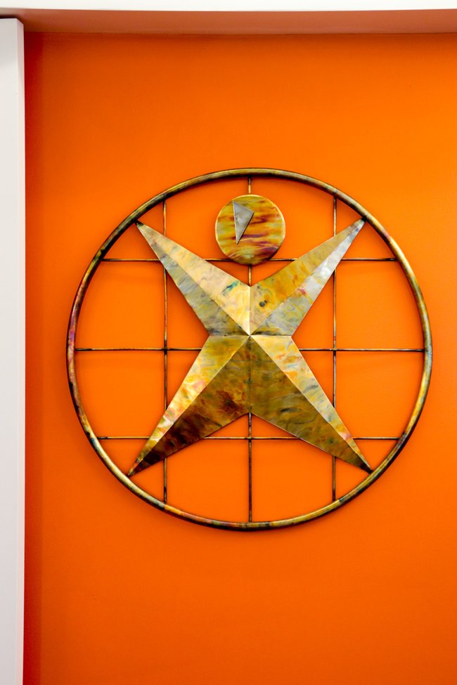 The Anderson Peak Performance figure in metal on an orange wall